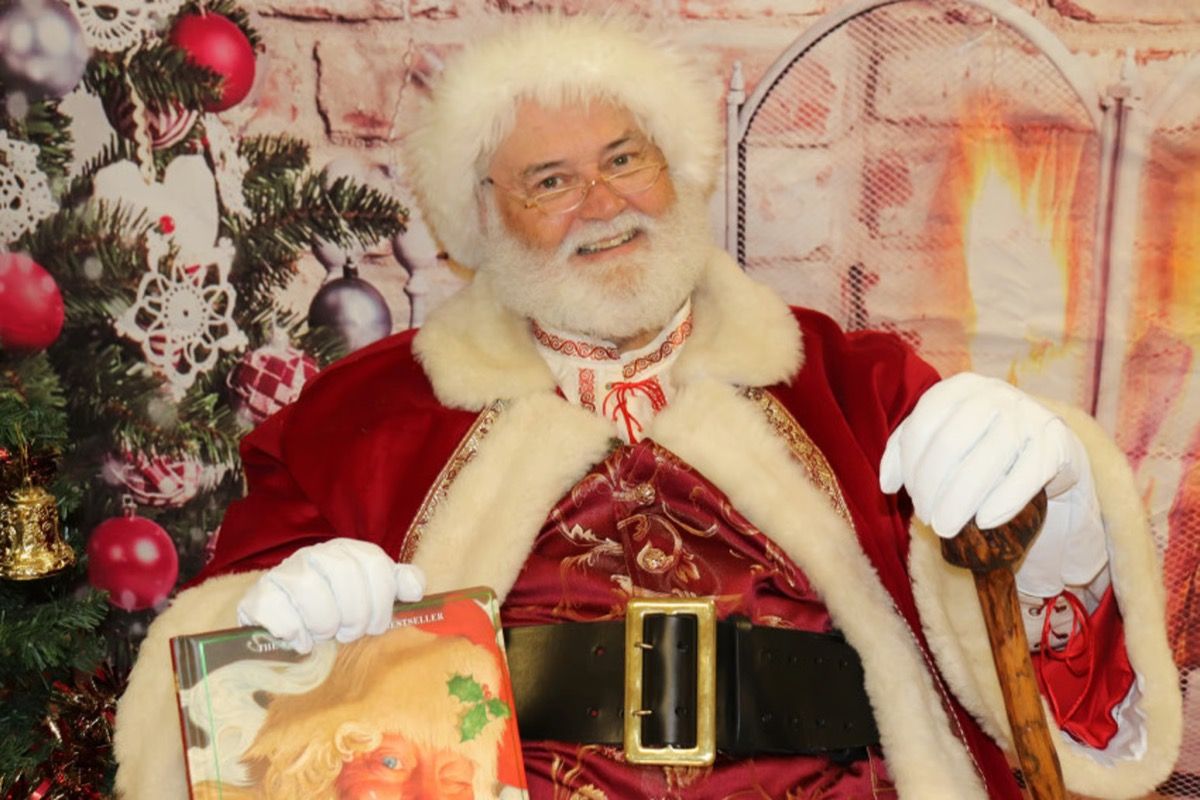 Santa Glenn posing indoors with a wrapped gift