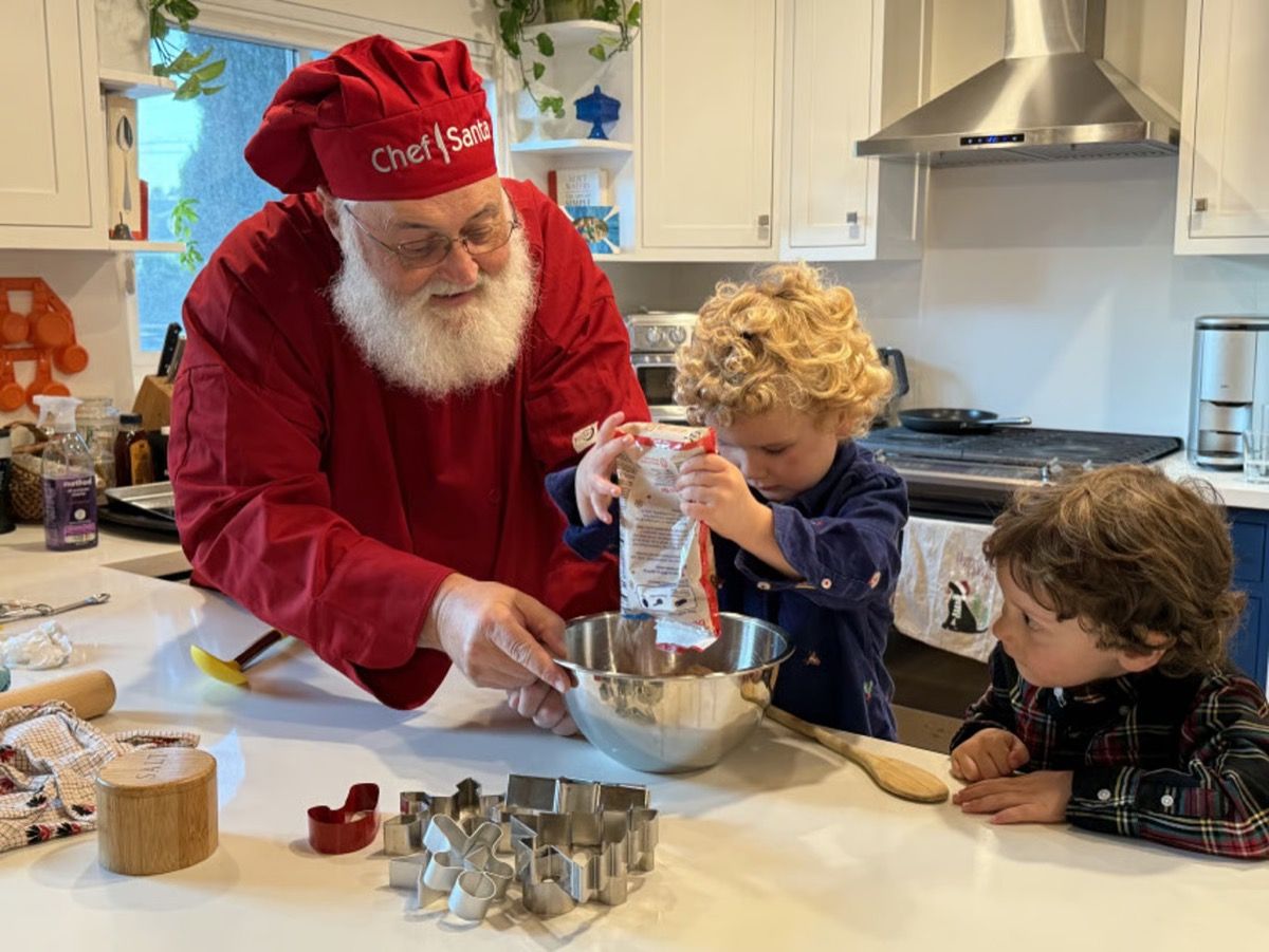 Santa Glenn, dressed as Chef Santa, baking cookies with children