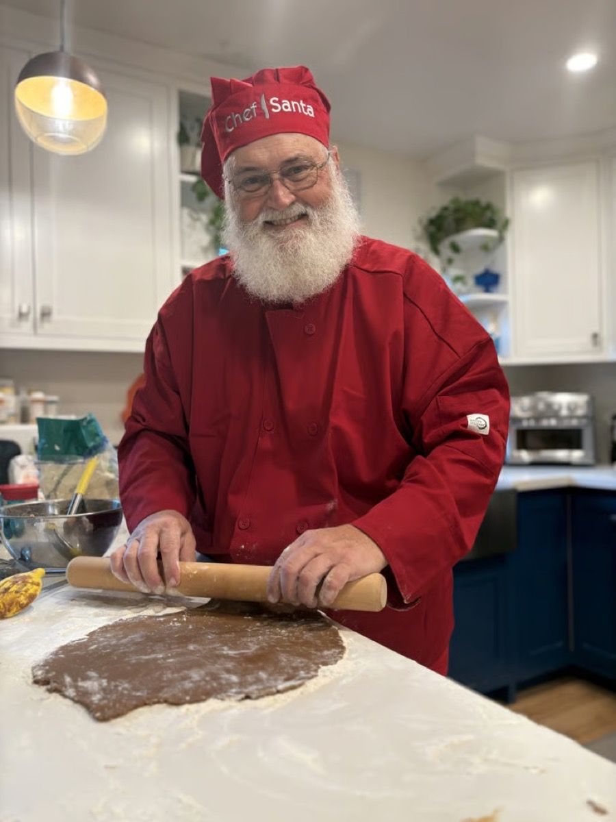 Santa Glenn, dressed as Chef Santa, rolling out cookie dough