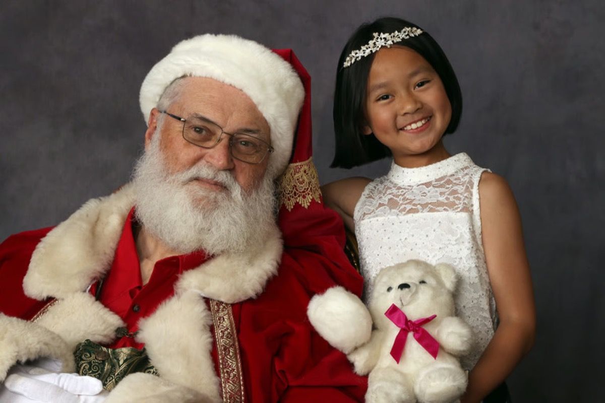 Santa Glenn with a girl in a tiara holding a teddy bear